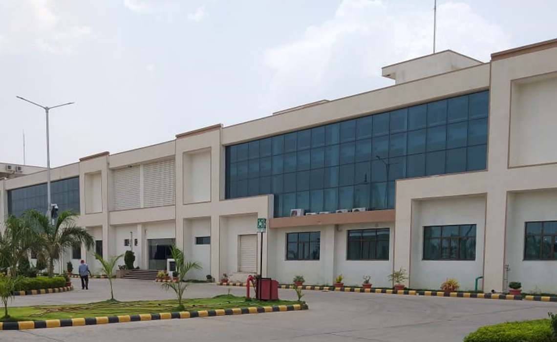 General view of a modern external textile mill facility with road access and neutral architecture