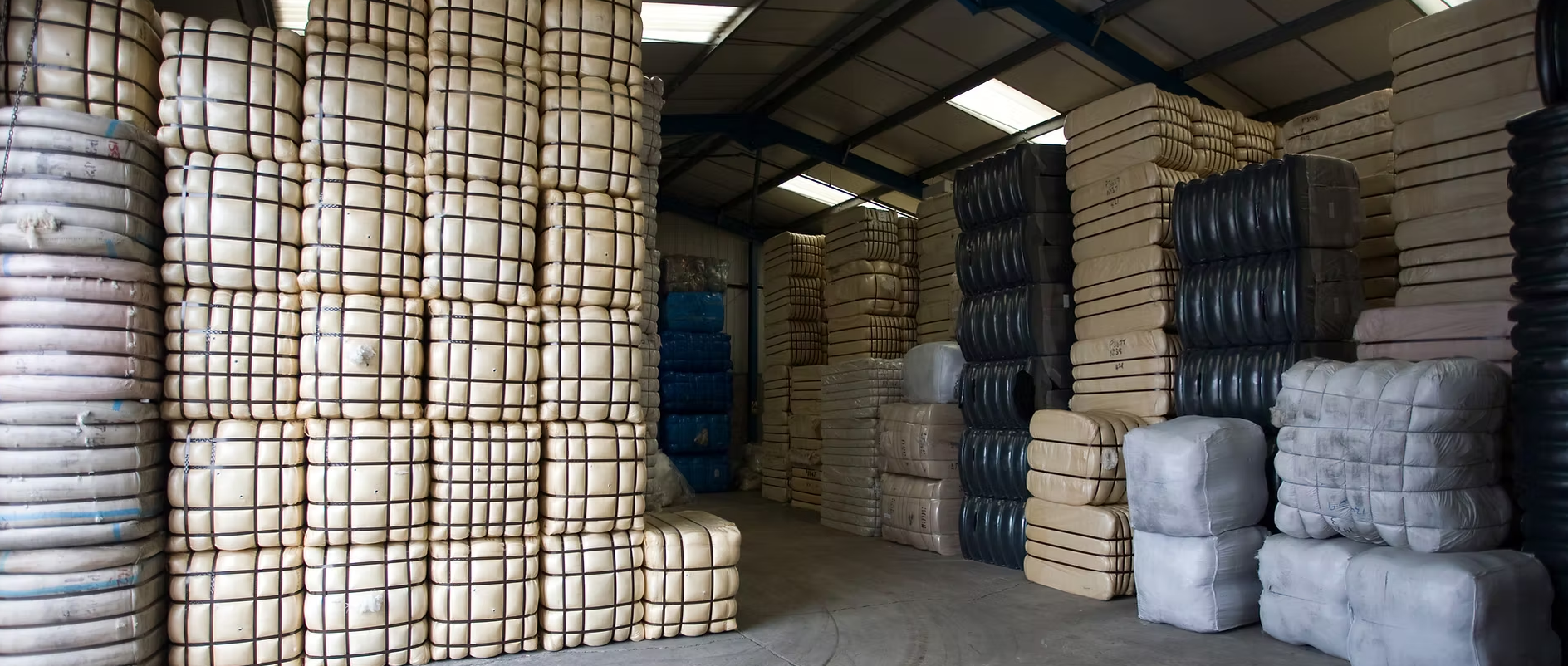Raw textile fiber bales stored in a clean, neutral-colored sourcing facility