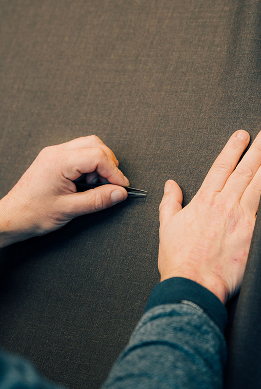 Close-up of hands checking texture and tension of fabric during weaving